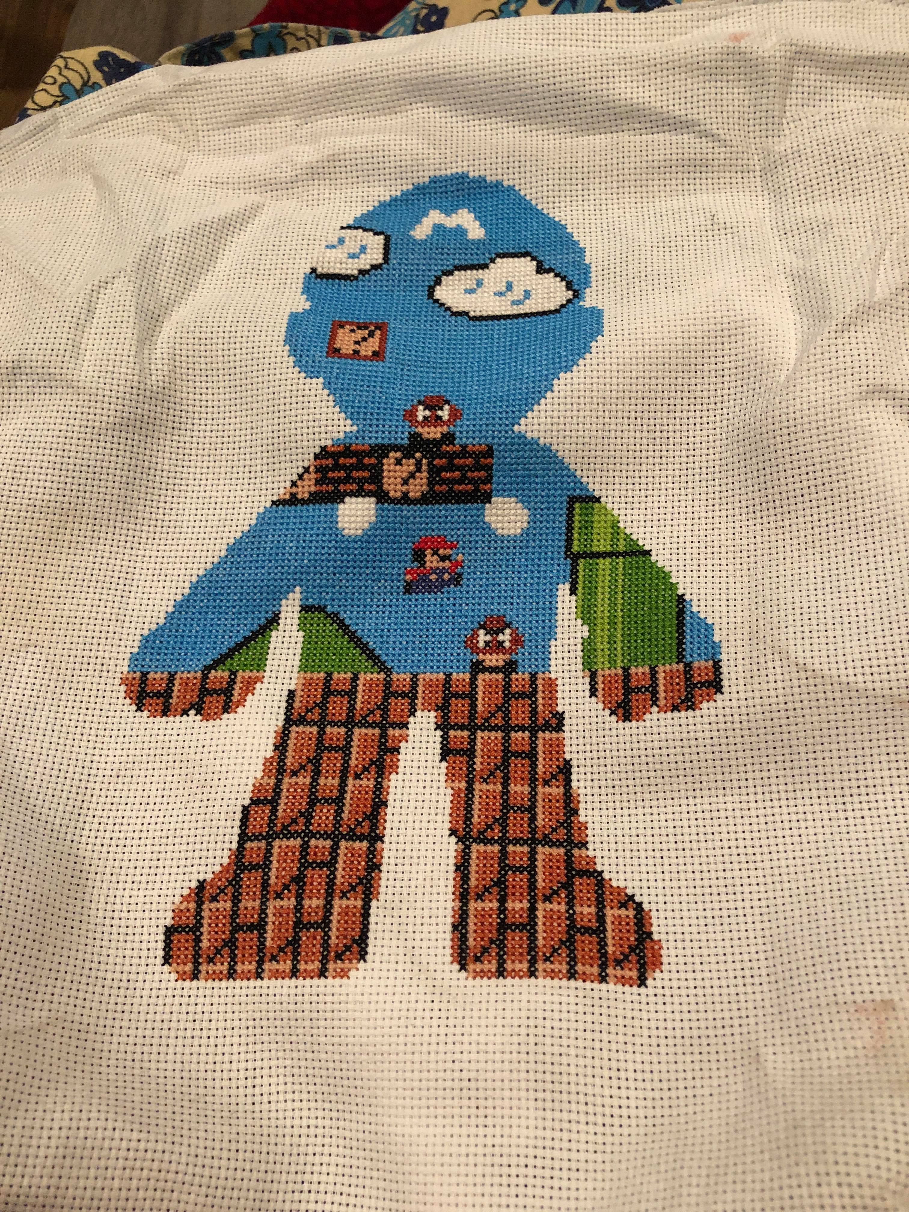 A cross stitch of the outline of Mario's body with a scene from original mario in it